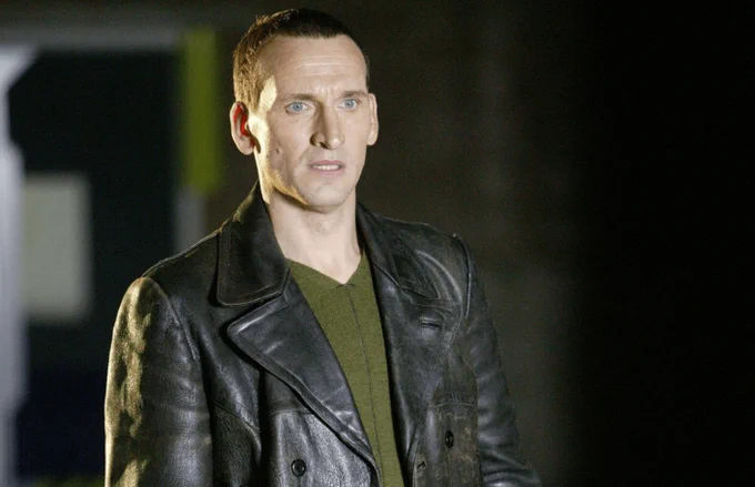 Christopher Eccleston as the Doctor wearing a leather jacket and green top.