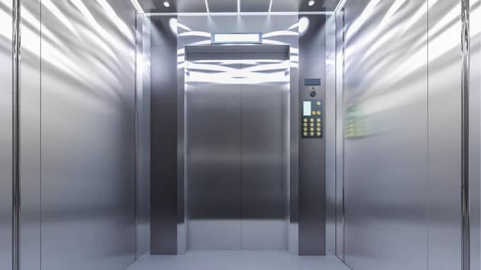 The inside of a lift, featuring its door, the passengers' space and the button panel. 
