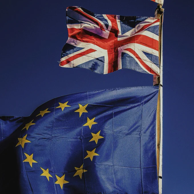 The flag of the United Kingdom flies on a flag pole next to the flag of the European Union.