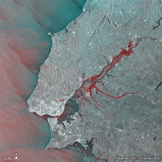 A radar‑based comparison image of the Tagus River region in Portugal using Copernicus Sentinel‑1 data from 27 December 2025 and 7 February 2026. Flooded areas are highlighted in bright red, spreading along the river and its tributaries northeast of Lisbon. The surrounding landscape appears in grey‑blue tones. Coastal areas and inland terrain are clearly visible, with a scale bar indicating 10 kilometres and a date label in the lower right corner.