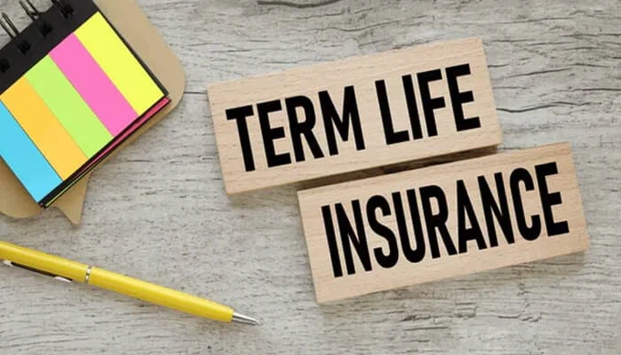Wooden blocks with the text 'Term Life Insurance' alongside a colorful sticky note and yellow pen on a desk