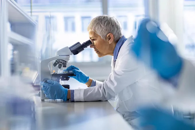 A person using a microscope in a lab. 