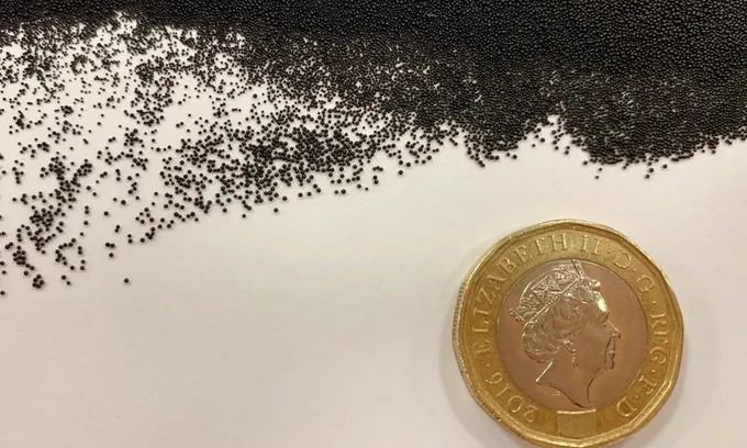 Thousands of small black Carbalive carbon beads next to a British pound coin for scale.
