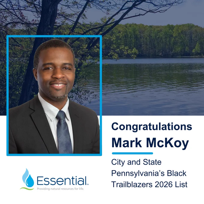 Top half of the background is a photo of a lake with trees in the background. Over the image is a blue overlay. Bottom half of the background is white. Picture of Mark McKoy on the left, with text on the right within the white reading “Congratulations Mark McKoy” as the title, and text under a light blue line saying “City and State Pennsylvania’s Black Trailblazers 2026 List”. To the left under Mark’s headshot is the Essential logo.