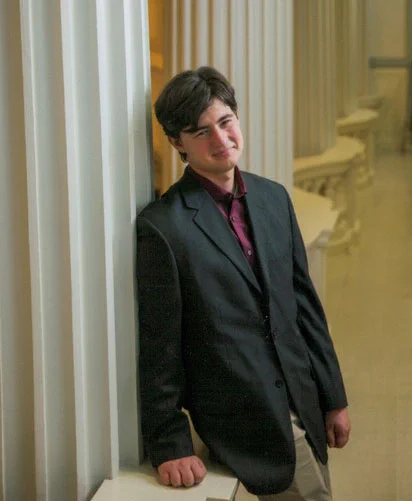 Portrait of Nathan Wagner, former Badger Precollege student and current undergraduate student at the University of Wisconsin-Madison. Her's wearing a black suit jacket with a maroon button-down shirt. He has short brown hair that's parted to the side.