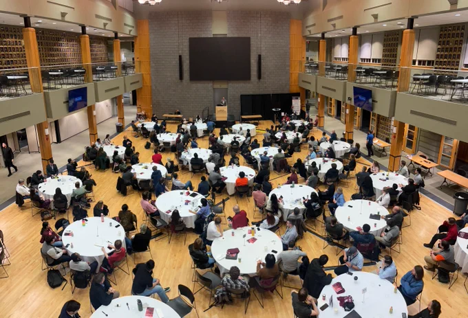 Attendees seated at round tables during Cyber Fusion 2026, listening to a speaker at a podium at Virginia Military Institute.