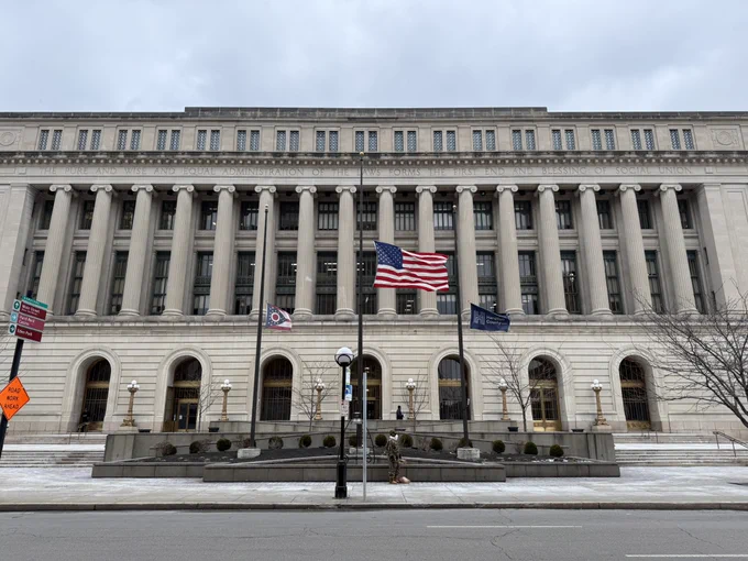 Front view of Courthouse with three flag poles with State, US, and County flags at half-staff 