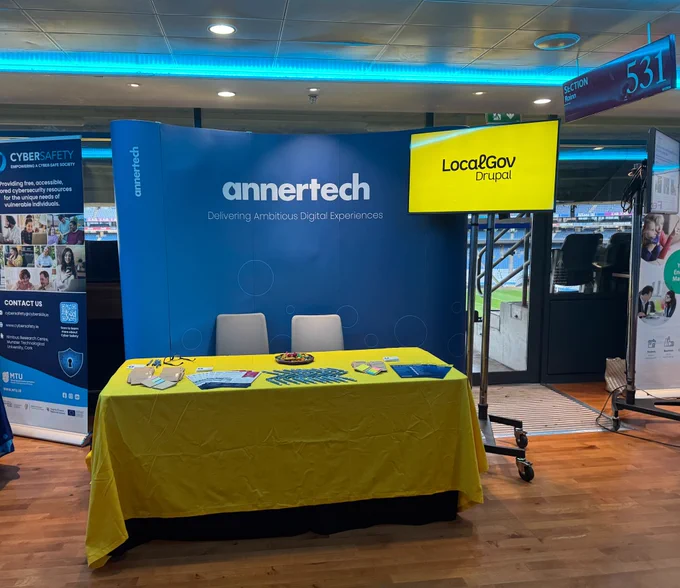 The Annertech booth at Digital Government 2026. The blue Annertech backdrop complements a LocalGov Drupal yellow table that holds pens, sticky notes and brochures.