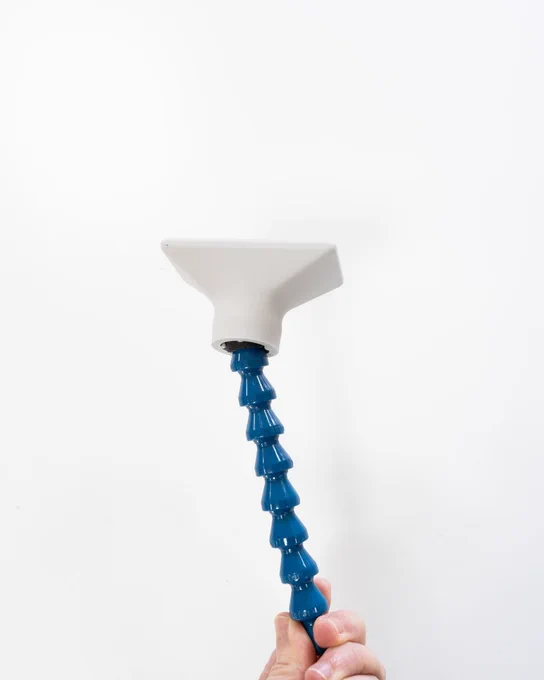 Primer plano de un puntero de licornio para boccia con brazo articulado azul y cabezal blanco impreso en 3D. Una mano lo sujeta desde la parte inferior.