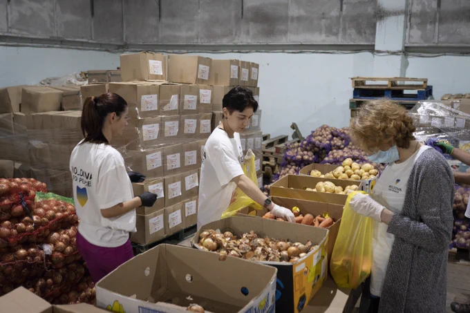 Volunteers (L-R) Yulia, Janna and Kristina pick fresh vegetables for DEC-funded Food & Hygiene kits for refugees at a distribution warehouse run by Plan International’s local partner Moldova for Peace in August, 2022.
