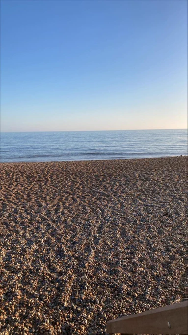 The blue sky, not a cloud in sight. Blue calm sea. Shingle beach. 