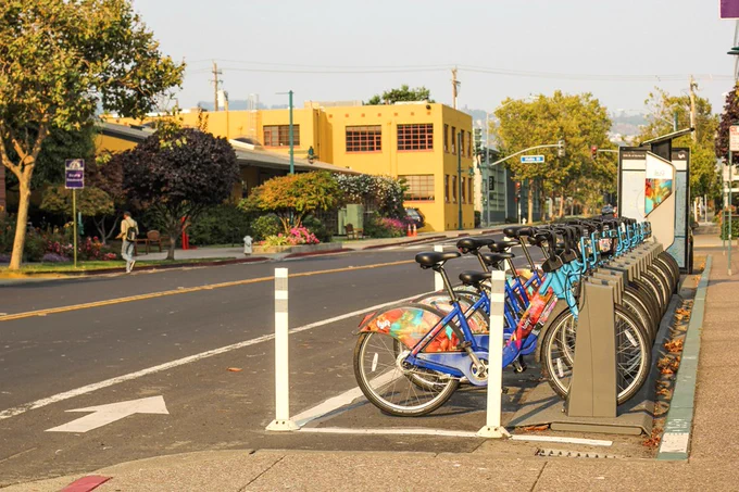 A line of bicycles at a docking station next to a street.