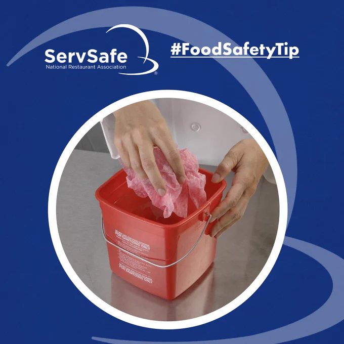 A person using a red sanitizing cloth to clean a red bucket. The image features the ServSafe logo and the hashtag #FoodSafetyTip on a blue background.