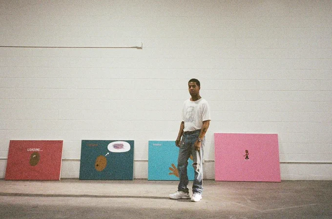 A person stands in a spacious, empty room with light-colored walls and a concrete floor. Four colorful canvases featuring abstract designs and text, are displayed behind the person.
