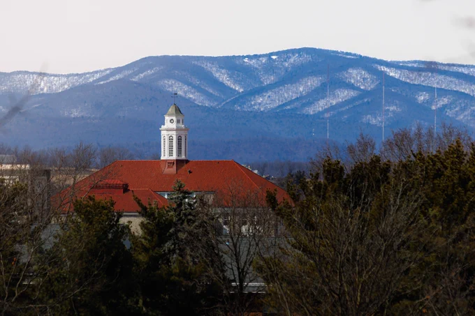 Wilson Hall stands in the foreground in front of snow-covered mountains.