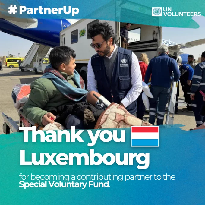 A UN Volunteers graphic with the hashtag #PartnerUp and the UN Volunteers logo. In the main image, a man wearing a World Health Organization vest assists a young boy on a stretcher as they disembark from a plane on an airport runway. Other humanitarian workers stand nearby. Overlaid text reads: “Thank you Luxembourg” with the Luxembourg flag, followed by “for becoming a contributing partner to the Special Voluntary Fund.