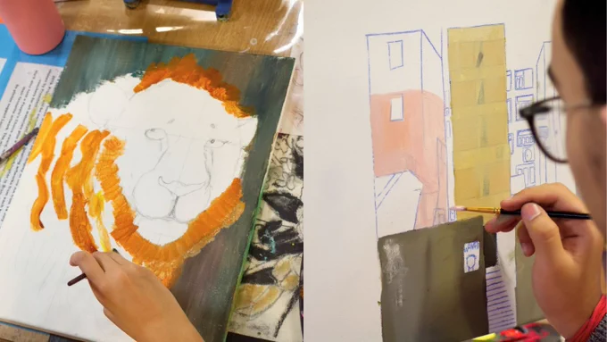 Two paintings in progress. On the left, a canvas features a partially painted lion with orange mane strokes. On the right, a canvas depicts an urban scene with block-like buildings in pastel colors. Two individuals are working on the paintings, each holding a paintbrush.