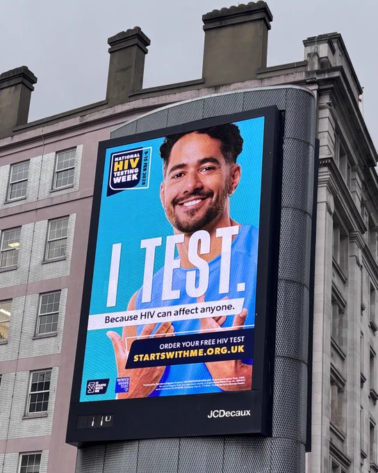 Billboard with a smiling man on it. Message reads 'I Test'.