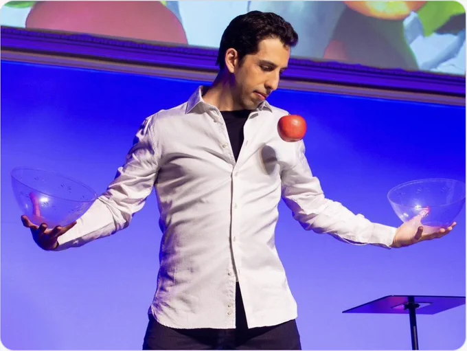 Vitaly Beckman has thrown an apple between two glass bowls, one in each hand.