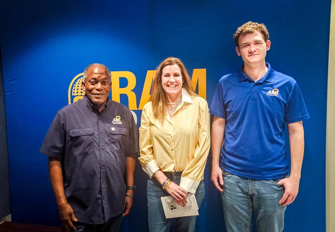 Three people standing in front of a backdrop posing for a photo. 