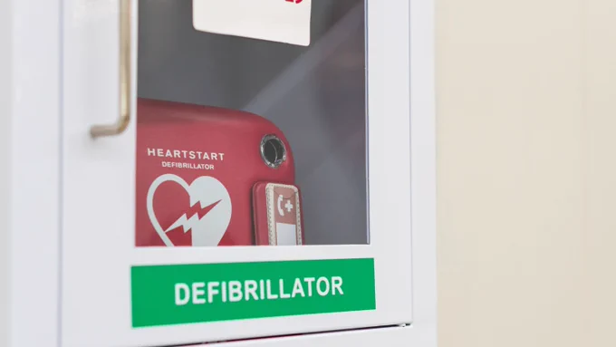 Defibrillator inside a clear box with a handle to open.