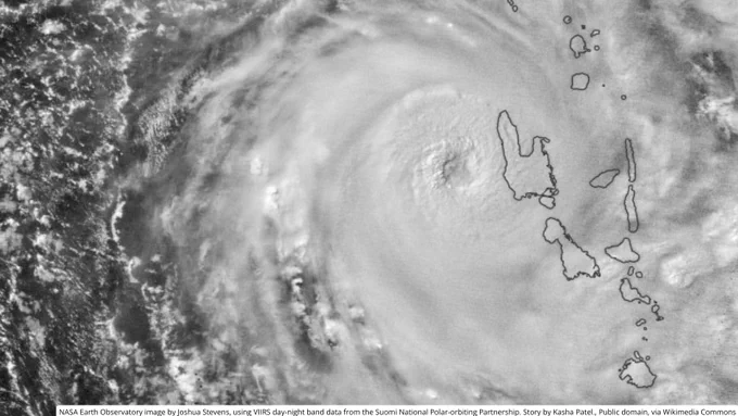 Satellite view of a large cyclone with a well-defined eye approaching a chain of islands in the ocean.