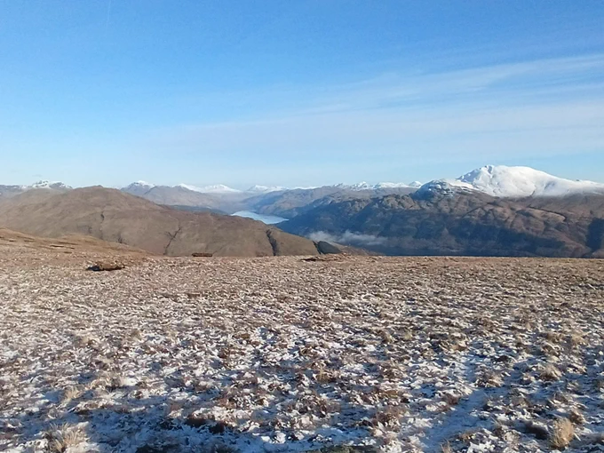 A snowy Loch Lomond hillside, blue skies and mountains all around