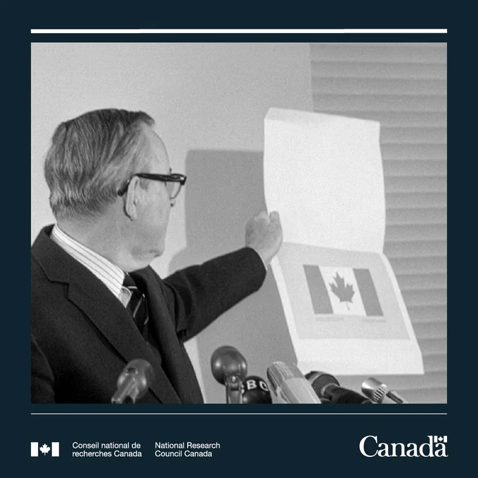 Le Premier ministre Lester B. Pearson tenant une illustration du nouveau drapeau canadien lors d'une conférence de presse en décembre 1964.