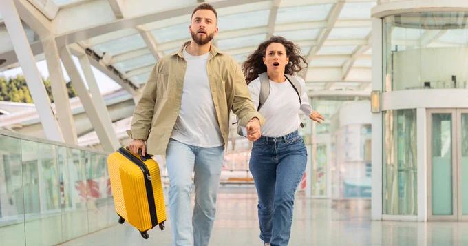 Couple running through station with suitcase