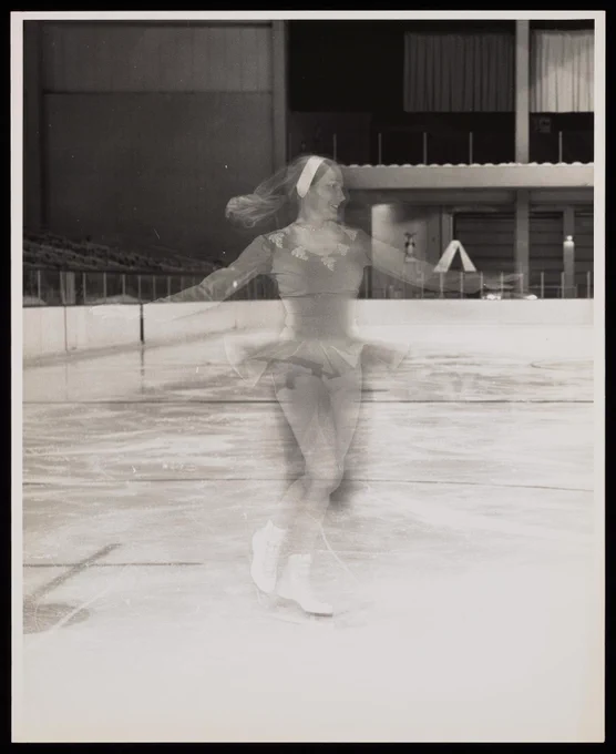 Photograph of a woman in a dress ice skating, appeared blurred as if spinning
