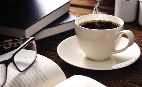 Background photo shows a reading table filled with open books.