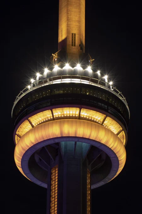 Closeup of the CN Tower at night lit in gold / Photo en gros plan de la Tour CN illuminée en or