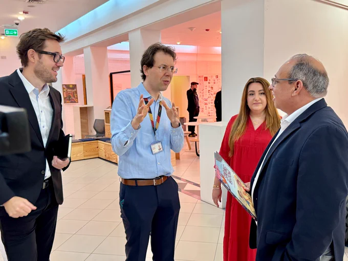 Dean Amir , matthias and summer from the liberal arts and sciences program , and Arturo talking in the corridor . Arturo is holding a book called spring bloom