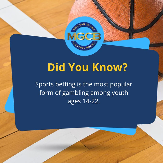 Close-up of a basketball on a wooden court with a Michigan Gaming Control Board message about youth sports betting.