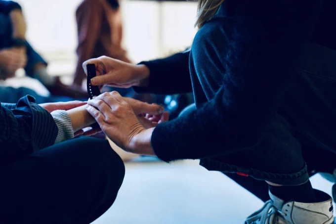 Two pairs of hands. One attaches a body sensor to the other's wrist.