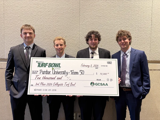 Otto Hoehl, Gavin Kenning, Abe Tebbe and Will Mahan holding a large ceremonial check for a Turf Bowl competition award
