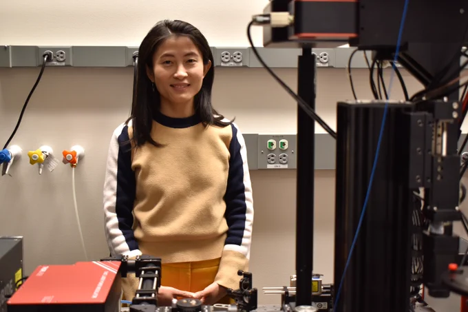 Linlin Fan stands among optical and microscopy equipment in her MIT lab