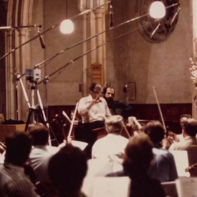 Brian De Palma looks on as Bernard Herrmann conducts his score for OBSESSION (1976).