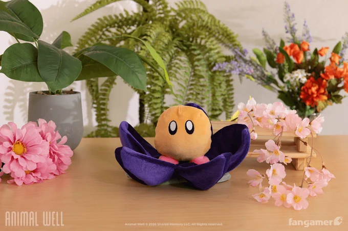 A photo of the Player Character Plush, new in our official Animal Well collection. It's a tiny round plush sitting in a plush flower