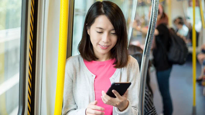 College student using a smartphone on a public train.