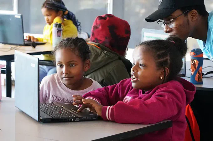 IMAGE : De jeunes enfants, dans une salle de classe, interagissent avec un ordinateur portable, sous la supervision d'un adulte. (Crédit photo : Réseau Engineering Outreach de la University of Waterloo)