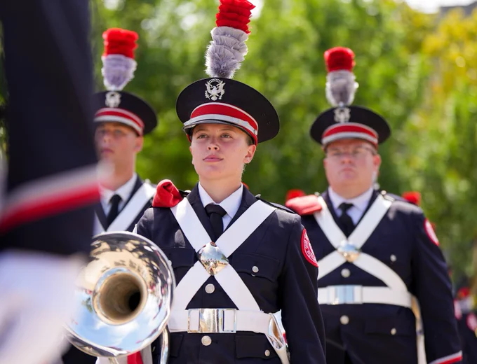 A marching band member holding a mellophone marching forward