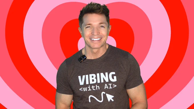 Photo of Tony smiling and wearing a shirt that says "Vibing with AI." Colorful hear background.