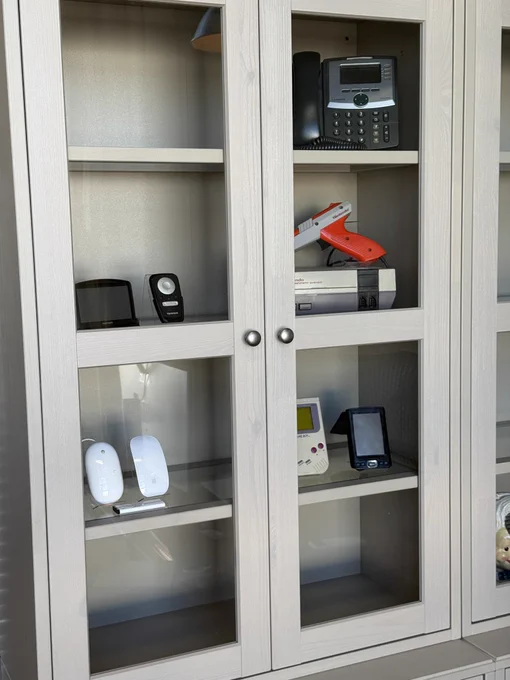 Cupboard with TomTom, Gameboy, NES, old phone, and old Apple mice.
