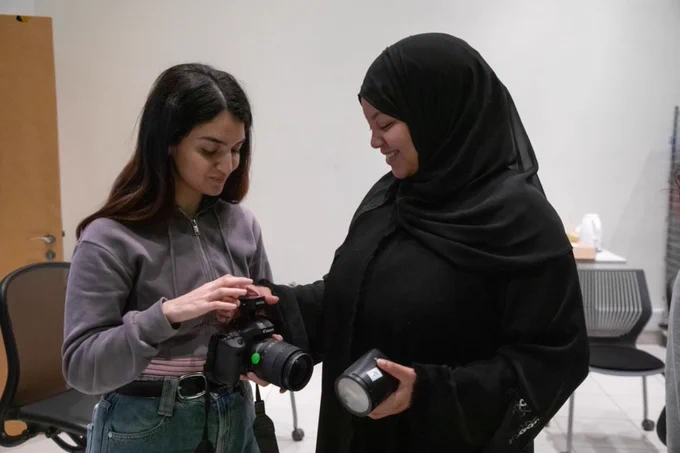 Two students examining camera equipment