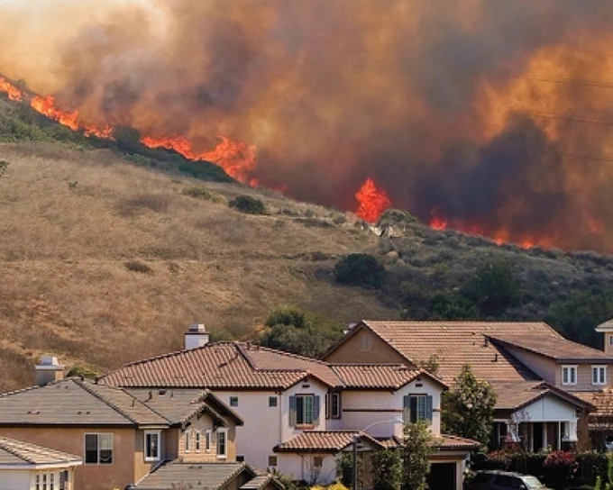 Hillside wildfire with flames and smoke near residential area with several houses. Photo credit: FEMA
