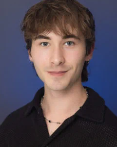 Photo of a student with short hair and black collared shirt taken in a studio setting