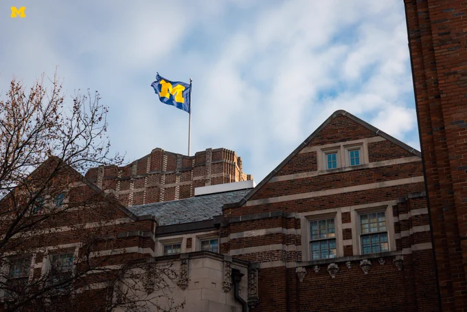 The sun shining through the clouds on the Block M flag atop the Michigan Union on a February morning.
