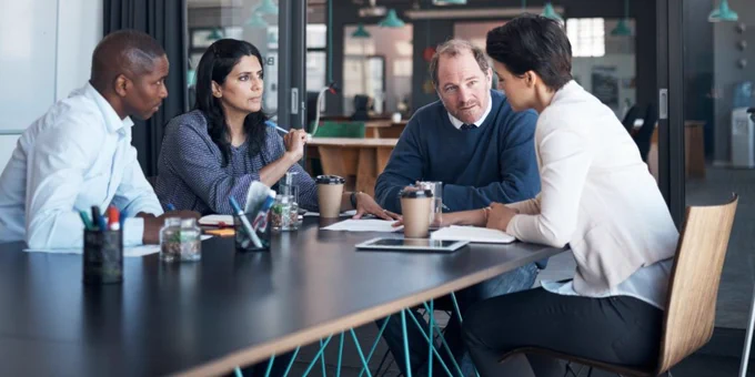 A group of SPAC professionals engaged in a meeting at a conference table in a modern office setting.