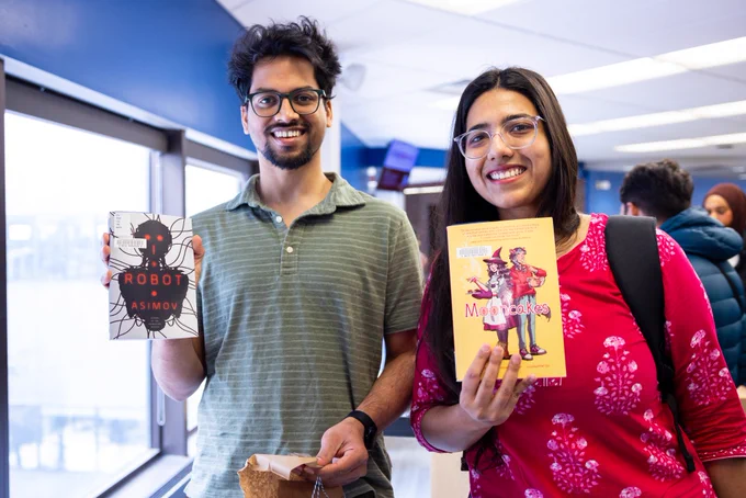 Students show off their surprise book selections after unwrapping